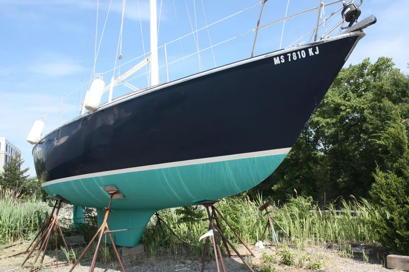 Slide: The Image of 1981 S2 9.2A sailboat on stands, dark blue hull, green bottom, outdoors. - 2