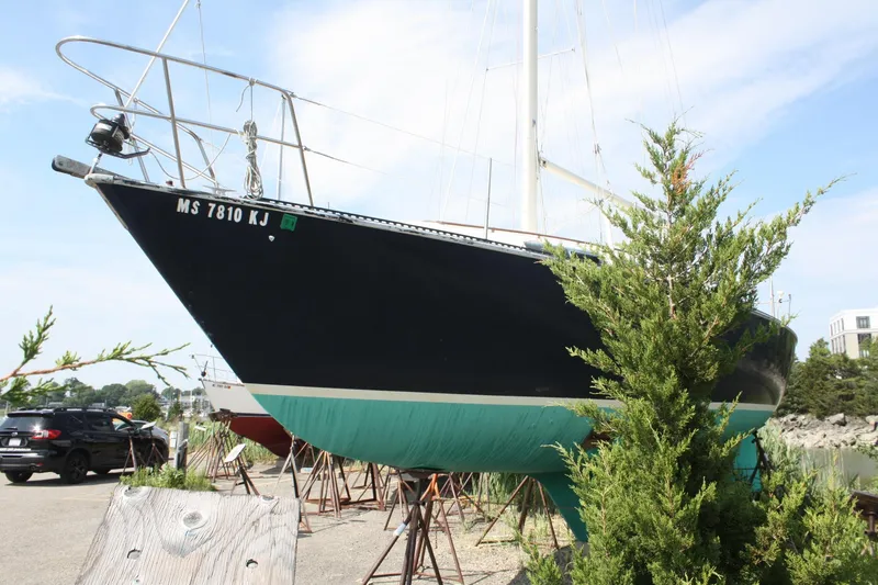 Slide: The Image of 1981 S2 9.2A sailboat on stands, partially obscured by greenery, in a boatyard setting. - 3