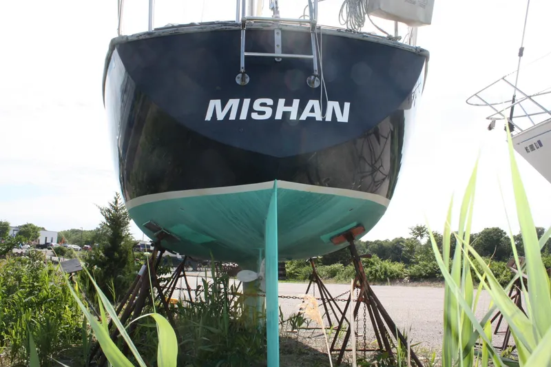 Slide: The Image of 1981 S2 9.2A sailboat named "Mishan" on stands, surrounded by greenery. - 6