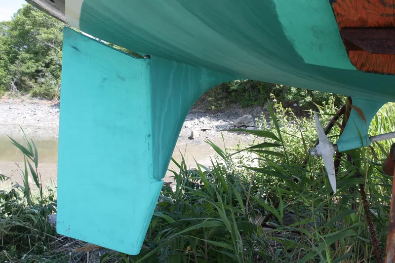Slide: The Image of 1981 S2 9.2A sailboat keel and propeller, turquoise hull, on dry land near riverbank. - 8
