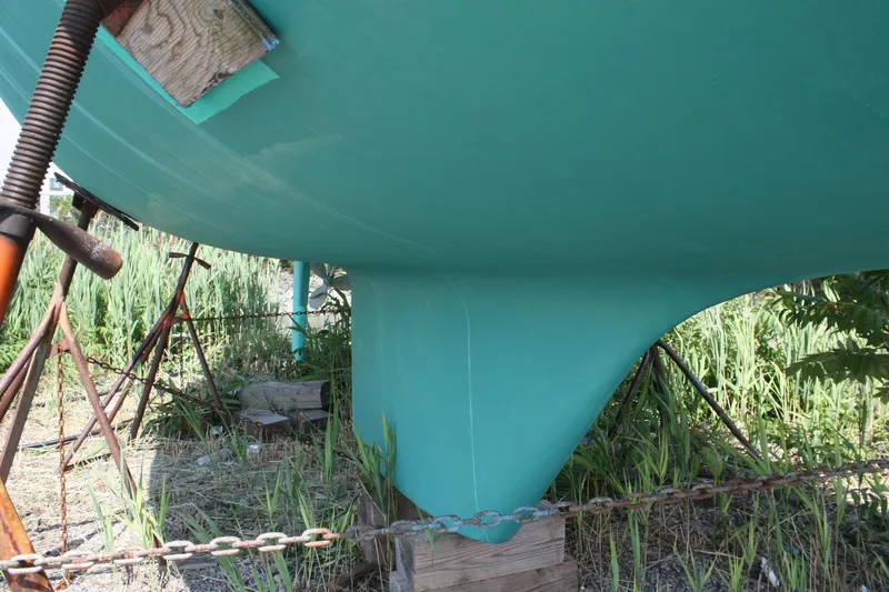 Slide: The Image of Bottom view of a 1981 S2 9.2A sailboat hull on stands, surrounded by grass. - 9