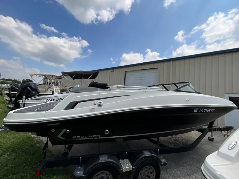 Slide: The Image of A 2023 Bayliner VR5 on a trailer in front of a building under a blue sky. - 2