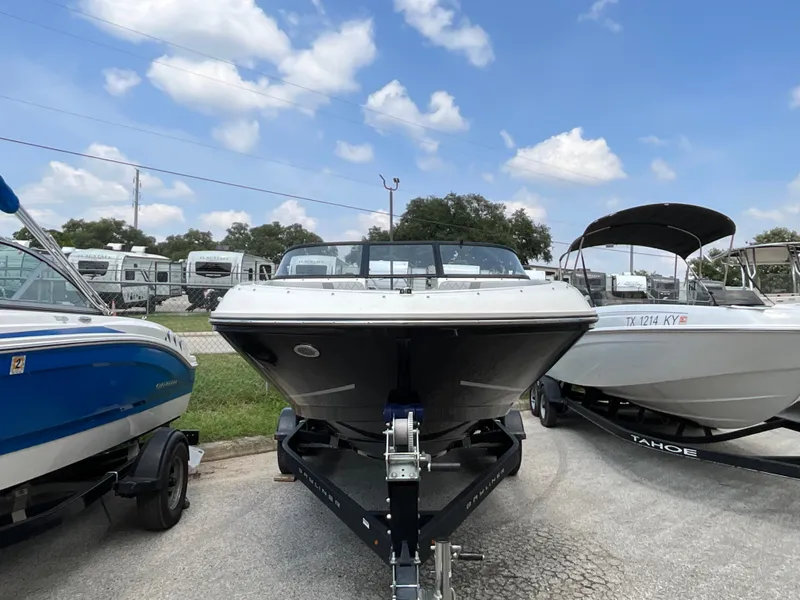 Slide: The Image of A 2023 Bayliner VR5 on a trailer, parked between other boats in a lot. - 3