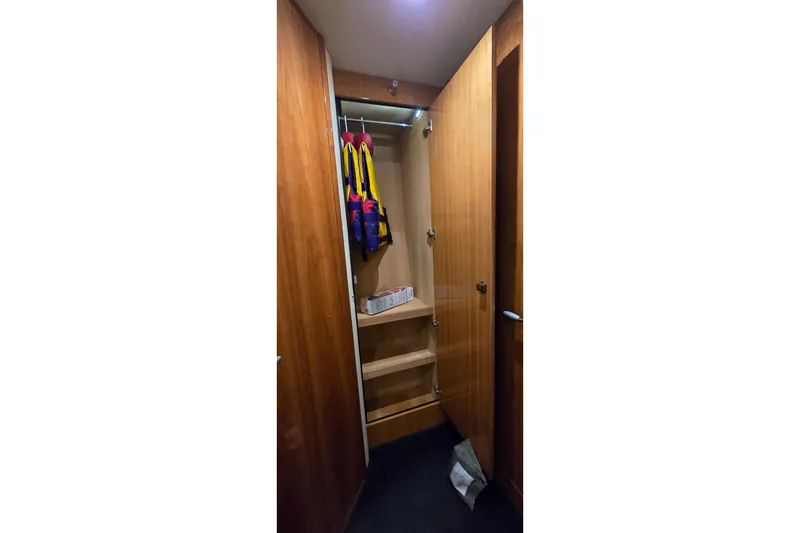 Slide: The Image of Wooden closet interior on 2004 Sunseeker Camargue 50 yacht, featuring life jackets and shelves. - 45