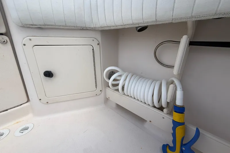 Slide: The Image of Coiled hose and storage compartment on 2000 Grady-White Express 265 boat. - 101