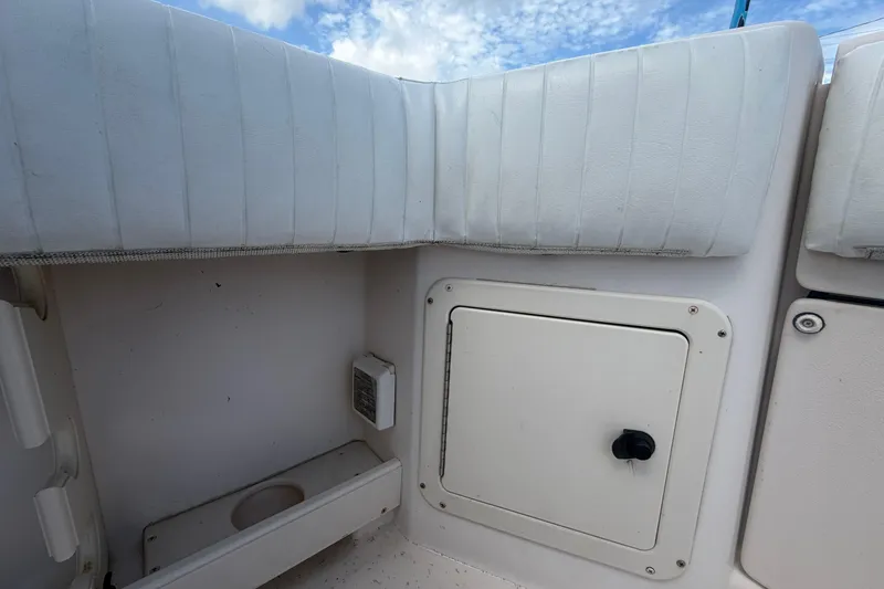 Slide: The Image of Interior view of a 2000 Grady-White Express 265 boat, featuring white cushioned seating and storage compartment. - 103