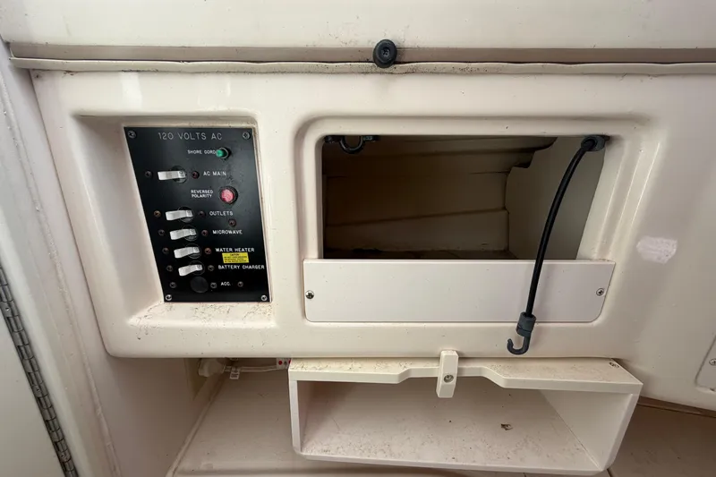 Slide: The Image of Electrical panel on a 2000 Grady-White Express 265 boat, featuring AC controls and storage. - 62