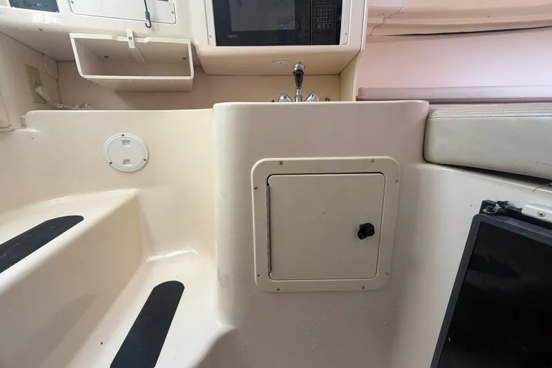 Slide: The Image of Interior of a 2000 Grady-White Express 265 boat, featuring a compact kitchenette. - 68