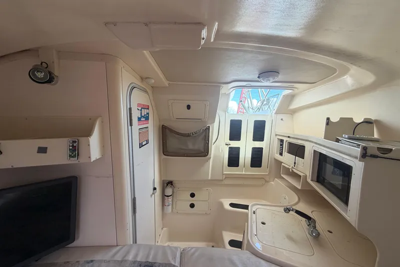 Slide: The Image of Interior of 2000 Grady-White Express 265 boat, featuring compact kitchen and storage areas. - 76