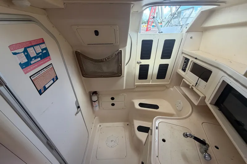 Slide: The Image of Interior of a 2000 Grady-White Express 265 boat, featuring a compact kitchenette and storage area. - 77