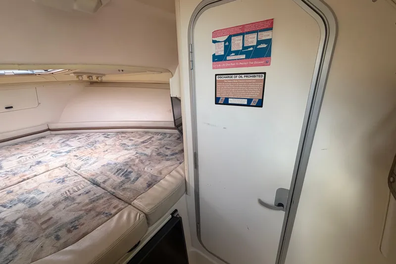 Slide: The Image of Interior cabin of 2000 Grady-White Express 265 boat with bed and informational signage. - 78