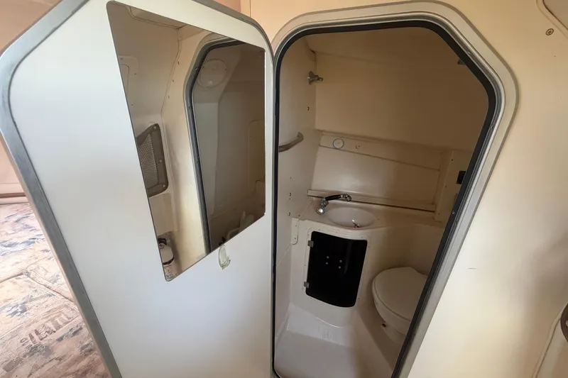 Slide: The Image of Compact bathroom inside a 2000 Grady-White Express 265 boat, featuring a sink and toilet. - 79