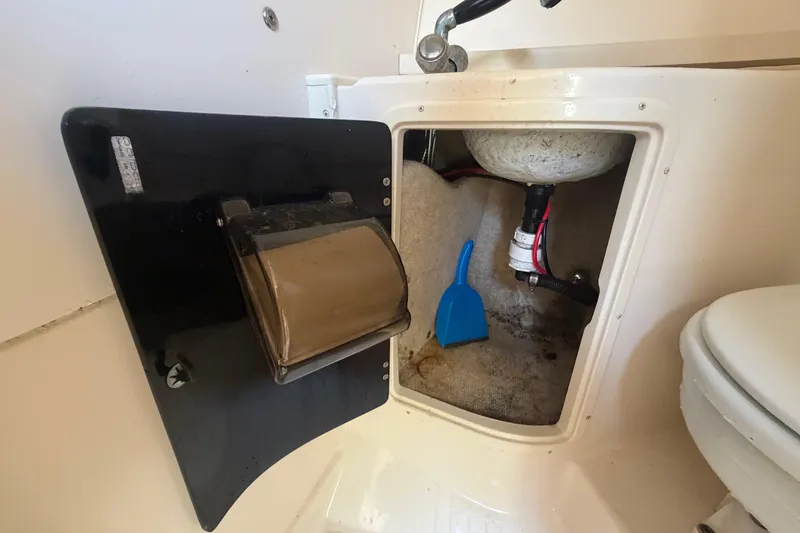 Slide: The Image of Storage compartment in a 2000 Grady-White Express 265 boat, featuring a blue dustpan. - 82