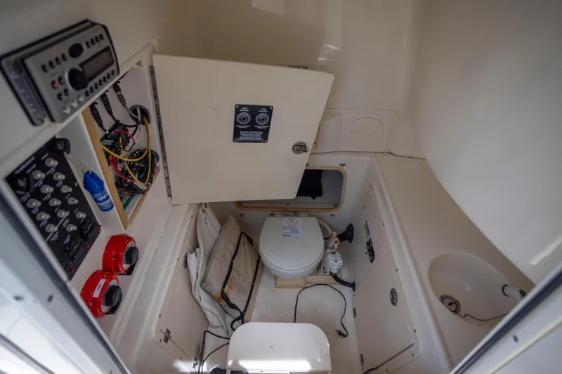 Slide: The Image of Interior of a 2007 Boston Whaler 270 Outrage boat, featuring a compact marine toilet. - 2