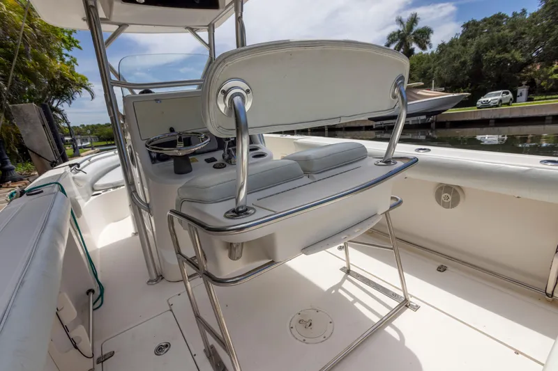 Slide: The Image of 2007 Boston Whaler 270 Outrage boat interior with helm and seating, docked by a canal. - 3