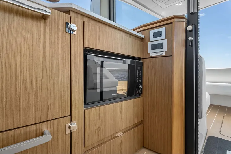 Slide: The Image of 2025 Tiara Yachts EX 60 interior with wood cabinetry and built-in microwave. - 64
