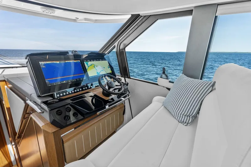 Slide: The Image of 2025 Tiara Yachts EX 60 helm with advanced navigation screens and luxurious seating. - 55