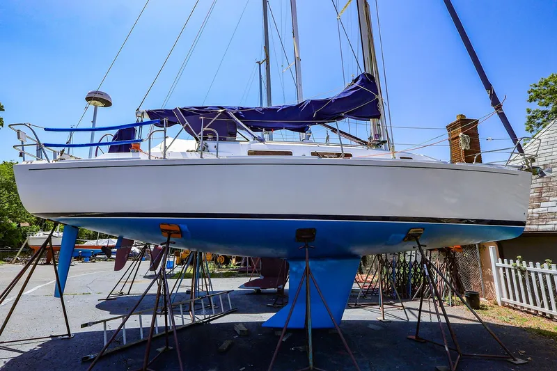 The Image of 2001 J Boats J/32 sailboat on stands, blue hull, outdoor setting. - 0