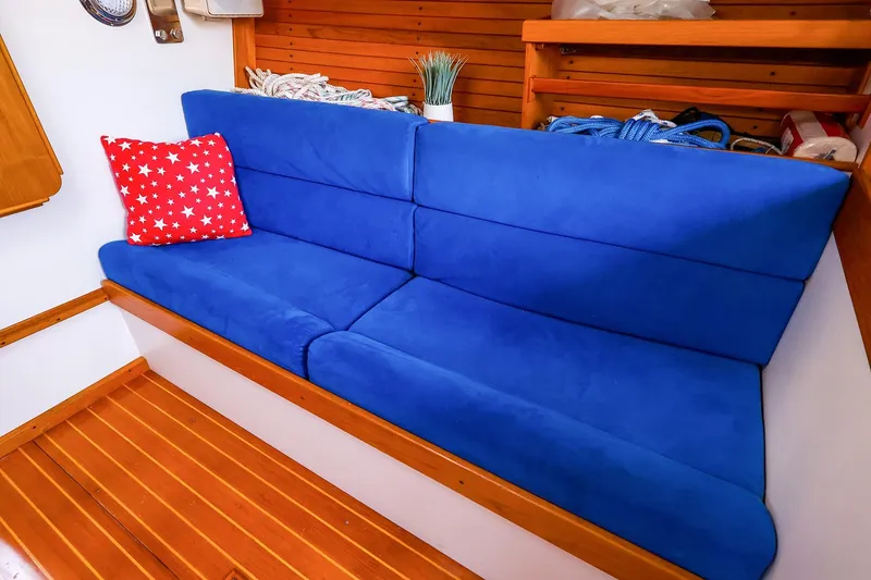Slide: The Image of Blue cushioned seating with red star pillow in 2001 J Boats J/32 interior. - 28