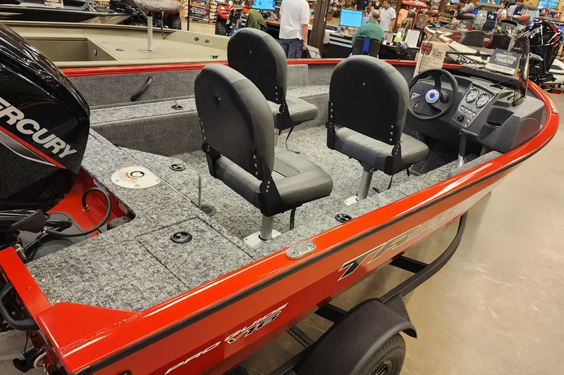 The Image of 2026 Tracker Pro Guide V-16 SC boat with red exterior and Mercury engine, displayed indoors. - 0