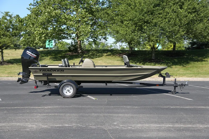 The Image of 2026 Tracker Grizzly 1754 SC boat on trailer in parking lot, surrounded by trees. - 0
