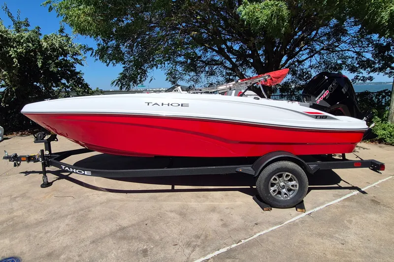 The Image of 2026 Tahoe T18 boat in red and white on a trailer, parked outdoors. - 0