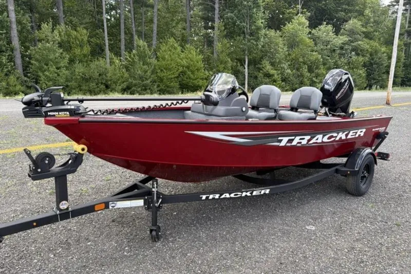 The Image of 2026 Tracker Super Guide V-16 SC boat on trailer, red color, parked outdoors. - 0