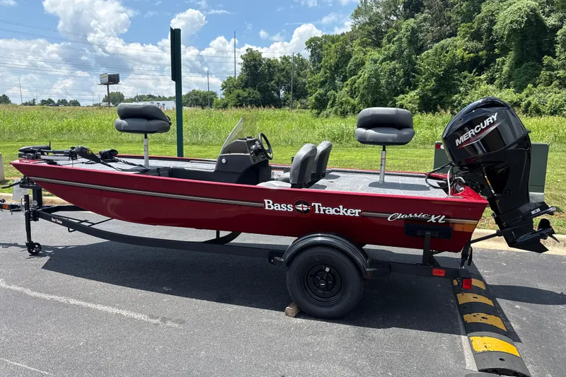 Slide: The Image of 2026 Tracker Bass Tracker Classic XL boat with Mercury engine on trailer, parked outdoors. - 2