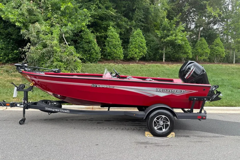 The Image of Red 2026 Ranger VS1665SC boat on trailer, parked on road with green foliage background. - 0