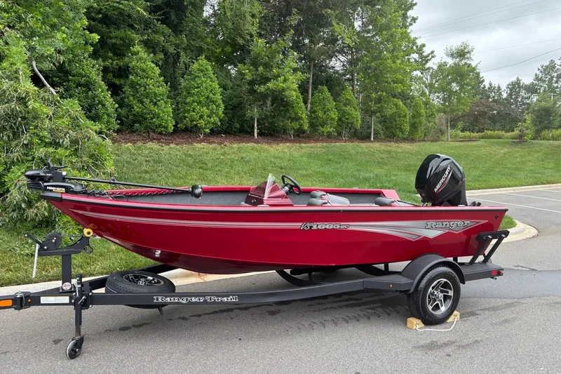 Slide: The Image of 2026 Ranger VS1665SC red fishing boat on trailer, parked near lush greenery. - 1