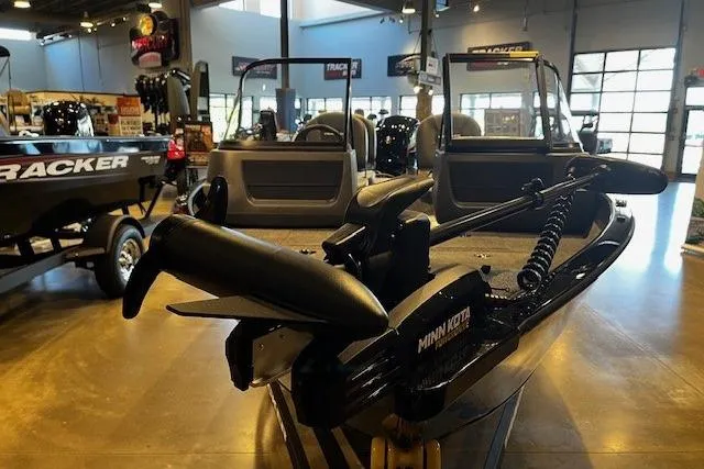 Slide: The Image of 2026 Tracker Pro Guide V-16 WT boat displayed in showroom with Minn Kota trolling motor. - 2