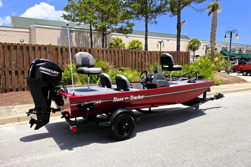Slide: The Image of 2026 Tracker Bass Tracker Classic XL boat with Mercury engine, parked outdoors. - 2