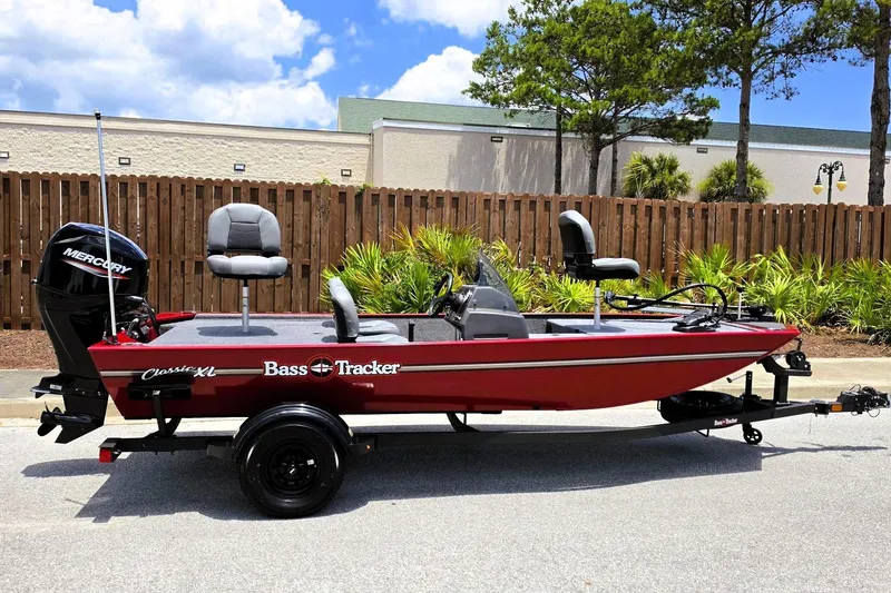 The Image of 2026 Tracker Bass Tracker Classic XL boat on trailer, red with Mercury motor, parked outdoors. - 0