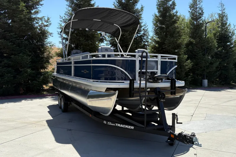 Slide: The Image of 2026 Sun Tracker Sportfish 24 XP3 pontoon boat on trailer, parked outdoors. - 5
