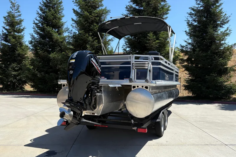 Slide: The Image of 2026 Sun Tracker Sportfish 24 XP3 pontoon boat with Mercury outboard motor, parked outdoors. - 7