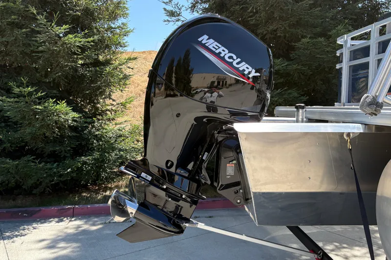 Slide: The Image of 2026 Sun Tracker Sportfish 24 XP3 with Mercury outboard motor, parked outdoors. - 9