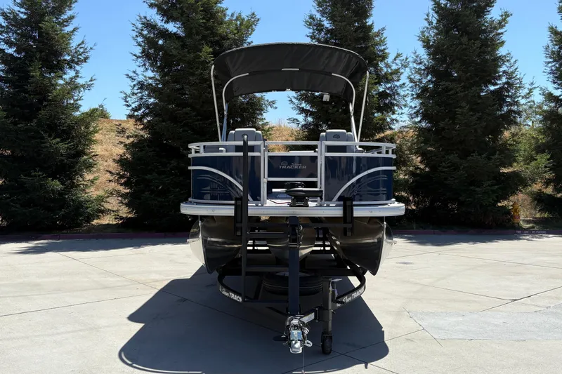 Slide: The Image of 2026 Sun Tracker Sportfish 24 XP3 pontoon boat on trailer, surrounded by trees. - 2