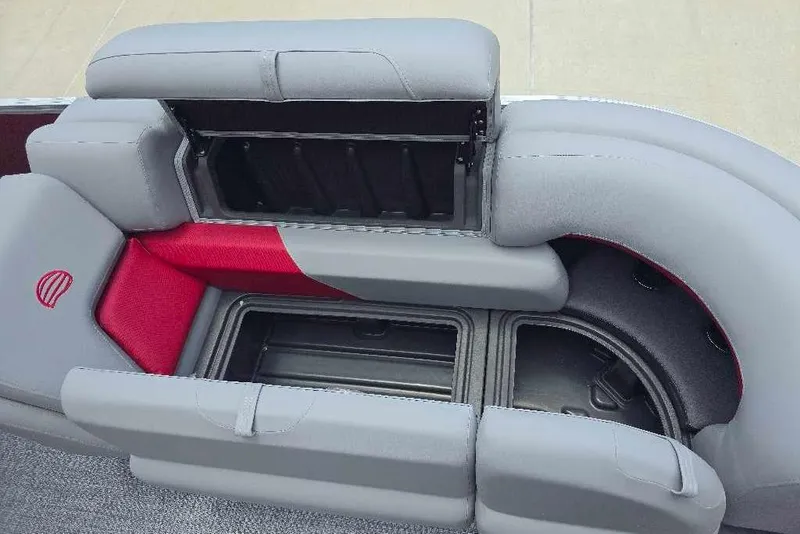 Slide: The Image of 2026 Sun Tracker Party Barge 20 DLX seating with storage compartments, featuring gray and red upholstery. - 7