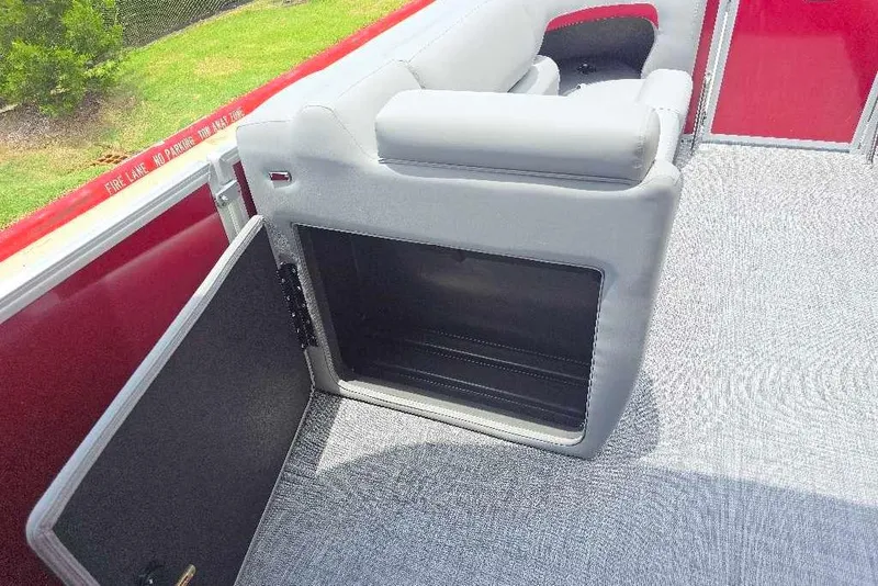 Slide: The Image of 2026 Sun Tracker Party Barge 20 DLX interior with open storage compartment and gray seating. - 9