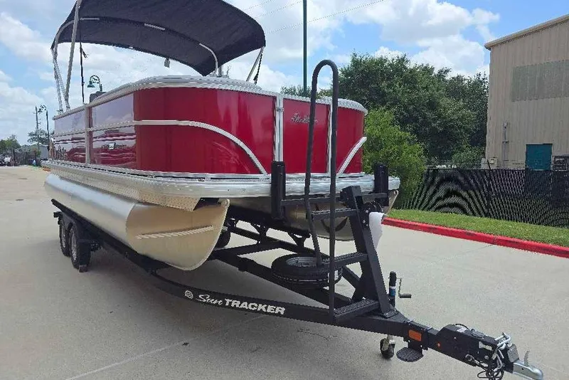 Slide: The Image of 2026 Sun Tracker Party Barge 20 DLX pontoon boat on trailer, red exterior, parked outdoors. - 3