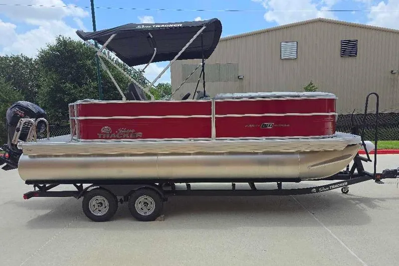 The Image of 2026 Sun Tracker Party Barge 20 DLX pontoon boat on trailer, red and silver design. - 0