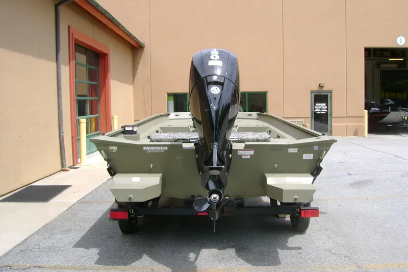 Slide: The Image of 2026 Tracker Grizzly 2072 CC boat with outboard motor, parked outside a building. - 4