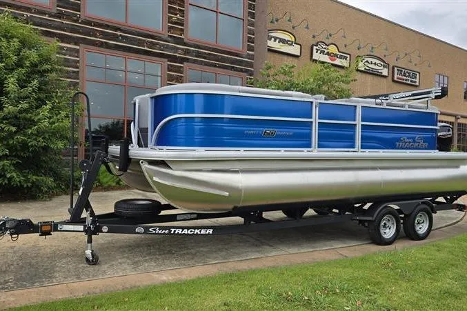 Slide: The Image of 2026 Sun Tracker Party Barge 20 DLX pontoon boat on trailer, parked outside dealership. - 5