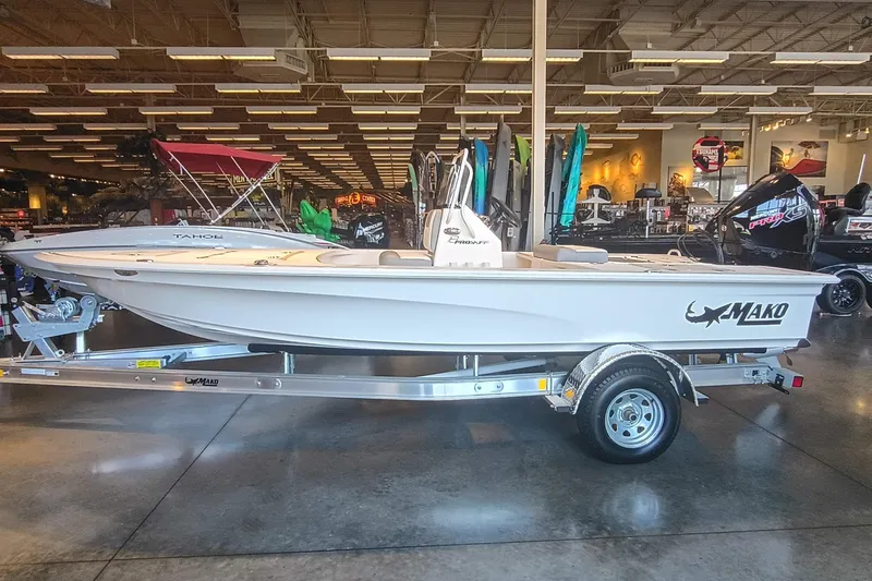 Slide: The Image of 2026 Mako 18 Pro Skiff boat displayed in a showroom on a trailer. - 2