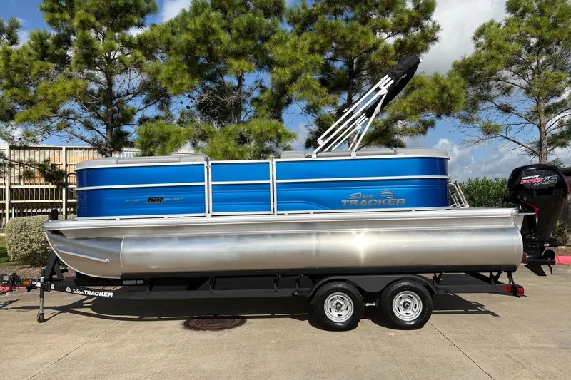 The Image of 2026 Sun Tracker Party Barge 20 DLX pontoon boat on trailer, parked outdoors. - 0
