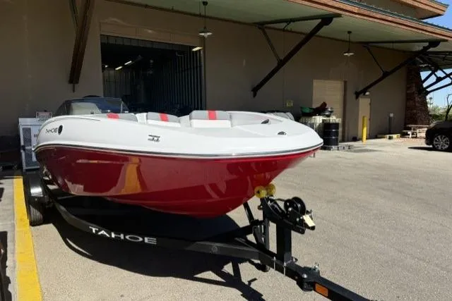 Slide: The Image of 2026 Tahoe T16 boat with red hull on trailer, parked outside a building. - 1