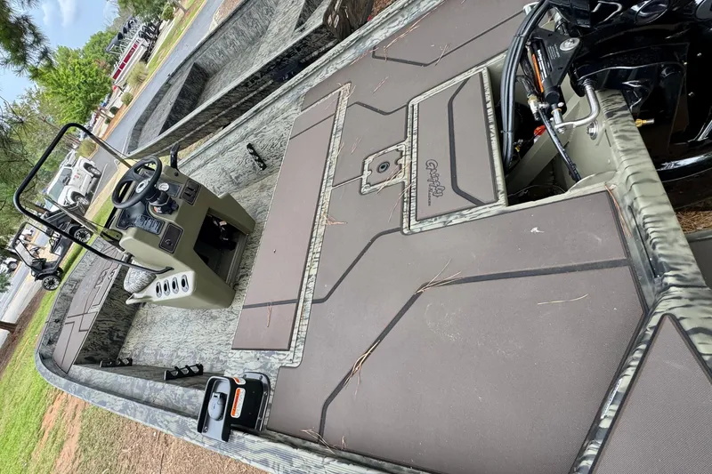 Slide: The Image of 2026 Tracker Grizzly 1860 CC boat interior with steering console and storage compartments. - 2
