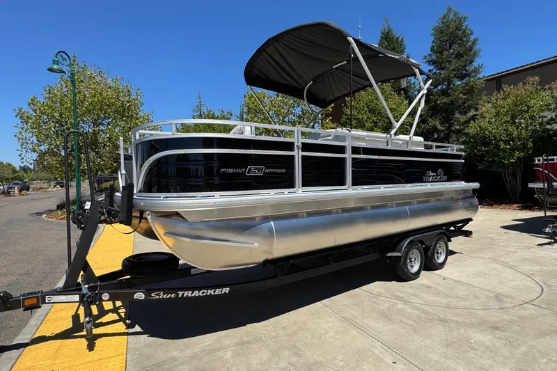 Slide: The Image of 2026 Sun Tracker Fishin' Barge 20 DLX pontoon boat on trailer, parked outdoors. - 3