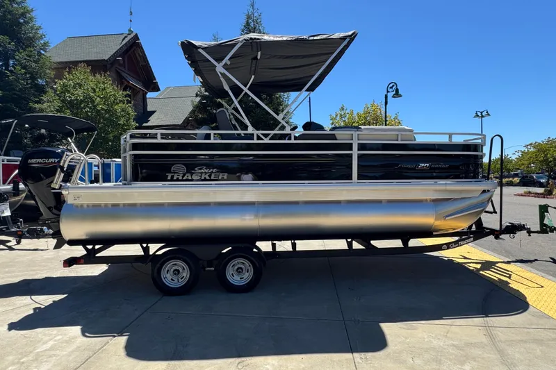 Slide: The Image of 2026 Sun Tracker Fishin' Barge 20 DLX pontoon boat on trailer, parked outdoors. - 2