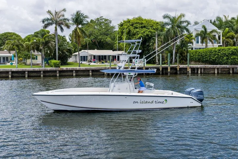 The Image of 1997 Venture 34 Center Console boat cruising near waterfront homes and palm trees. - 1